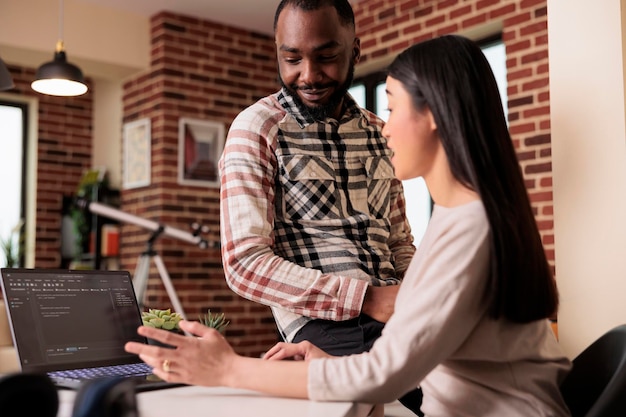 programmers couple developing encryption code on laptop, using terminal window with html script and binary code. programming online application cloud server with firewall security.