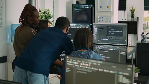 database admins collaborating on group project compiling algorithm for new cloud computing user interface on computer. multiethnic team of software engineers developing html script code.