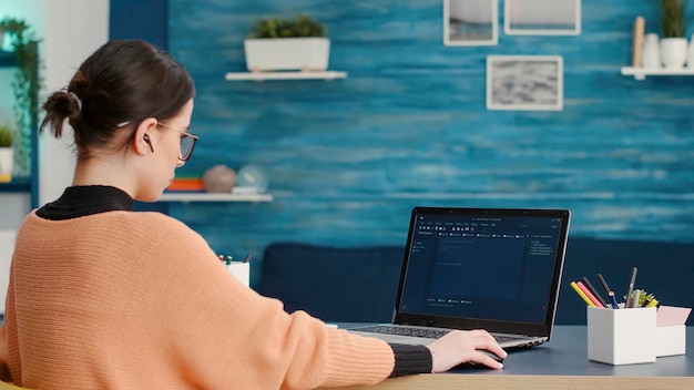female coder programming analytics report on technical interface, using hacking software to create binary code information and data. programmer using virtual system and network on laptop.
