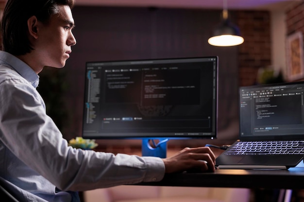 software developer coding firewall program on monitor and laptop, using encryption server to script security network with binary code. developing app on data text interface, it programming.