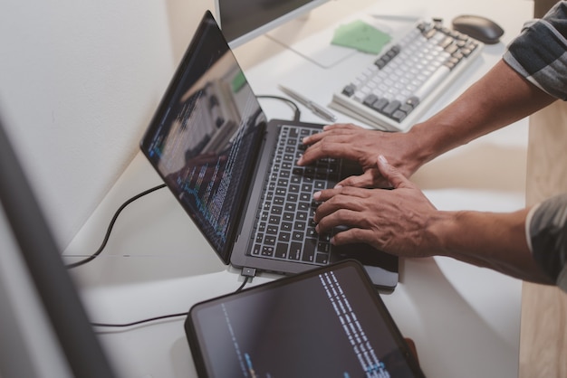 software developer coding on laptop and tablet in a modern workspace closeup of programming workflow software engineering debugging source code and multidevice application development